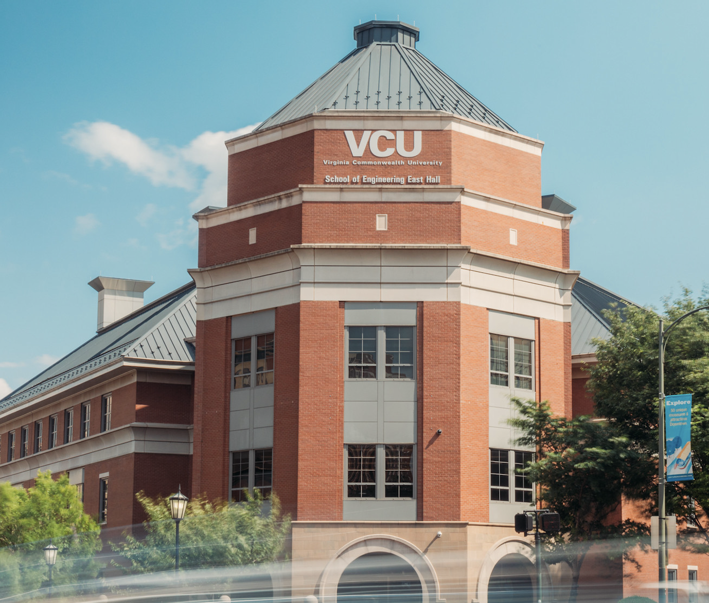 Image of the exterior of the VCU Engineering building with blurred cars moving in the street in front.